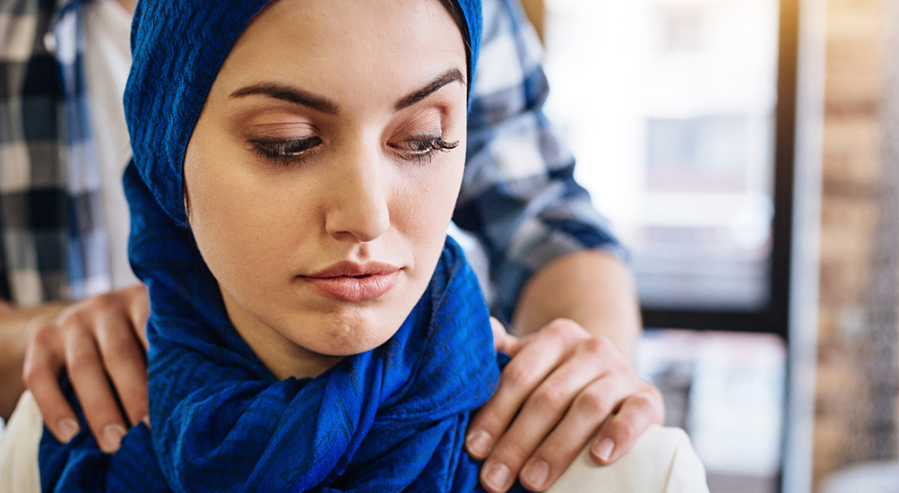 woman sitting with a man's hands on her shoulders